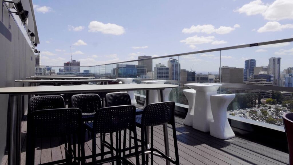 Terraza del hotel de Perth equipada con el sistema de megafonía y música ambiental Vocia de Biamp, con vistas a la ciudad.
