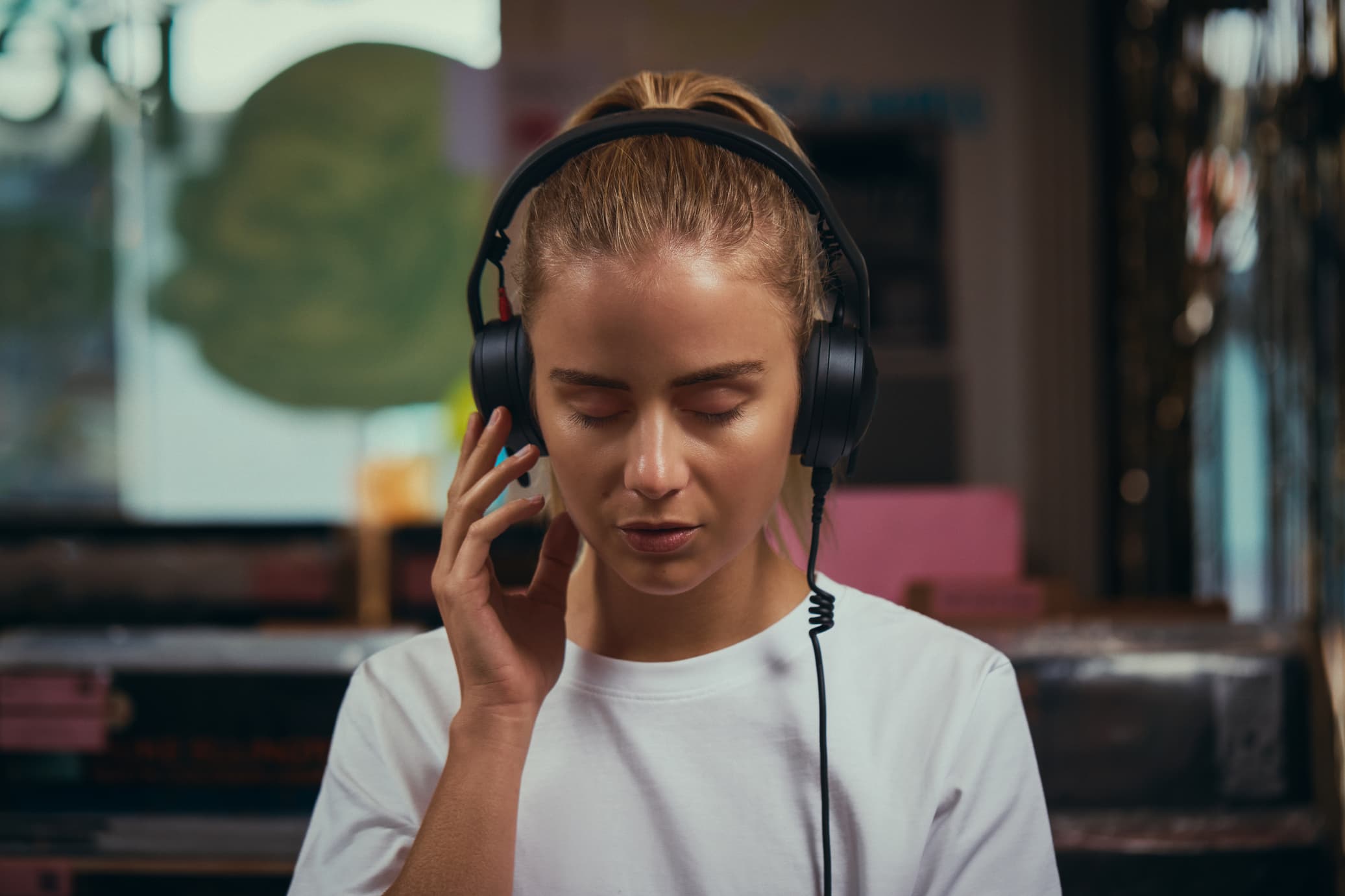 Mujer disfrutando de su música favorita con los auriculares RØDE NTH-50, ideales para uso diario gracias a su comodidad y fidelidad sonora, en un ambiente relajado y casual.