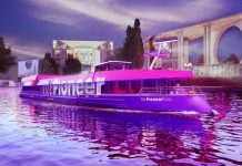 arco The Pioneer Two navegando por un canal urbano al atardecer, iluminado con luces fucsias, utilizado como plataforma de producción editorial móvil por Media Pioneer Publishing AG.