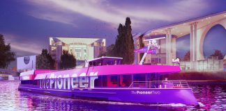 arco The Pioneer Two navegando por un canal urbano al atardecer, iluminado con luces fucsias, utilizado como plataforma de producción editorial móvil por Media Pioneer Publishing AG.
