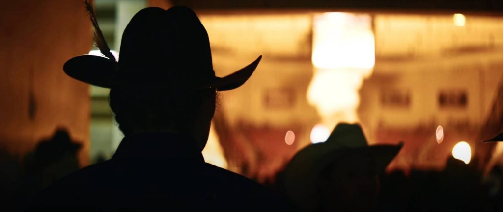Silueta de un jinete indígena durante el rodeo, con fondo iluminado en tonos cálidos, capturada con estilo cinematográfico gracias a la Blackmagic PYXIS 6K.