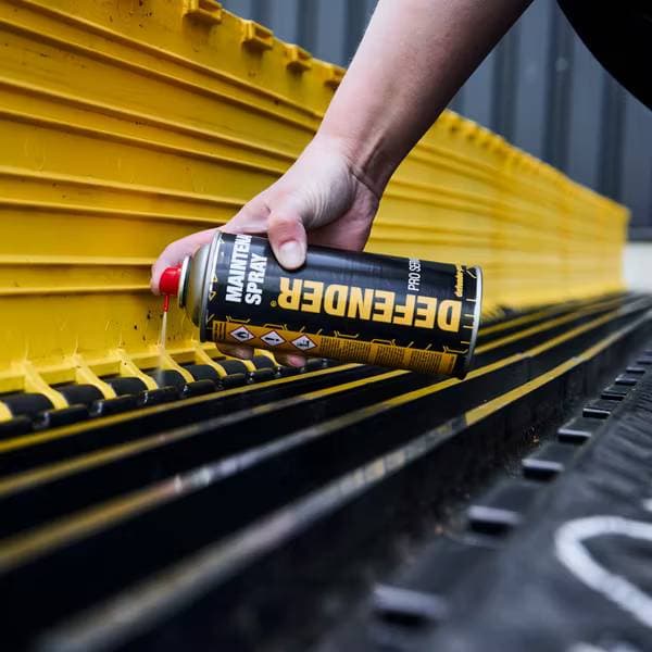 Aplicación del spray de mantenimiento de los protectores de cables DEFENDER sobre superficie de goma para prolongar su vida útil