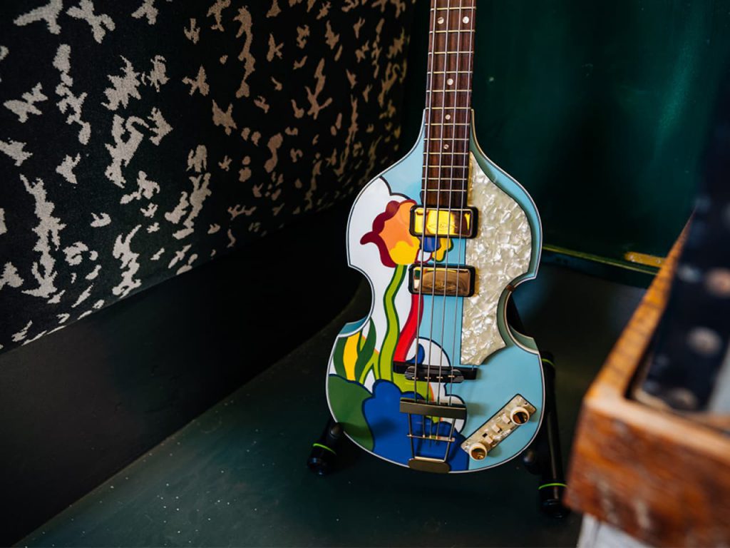 Bajo con diseño psicodélico expuesto en el autobús de la gira Wings de Paul McCartney, restaurado con motivo del 50 aniversario de Adam Hall Group.