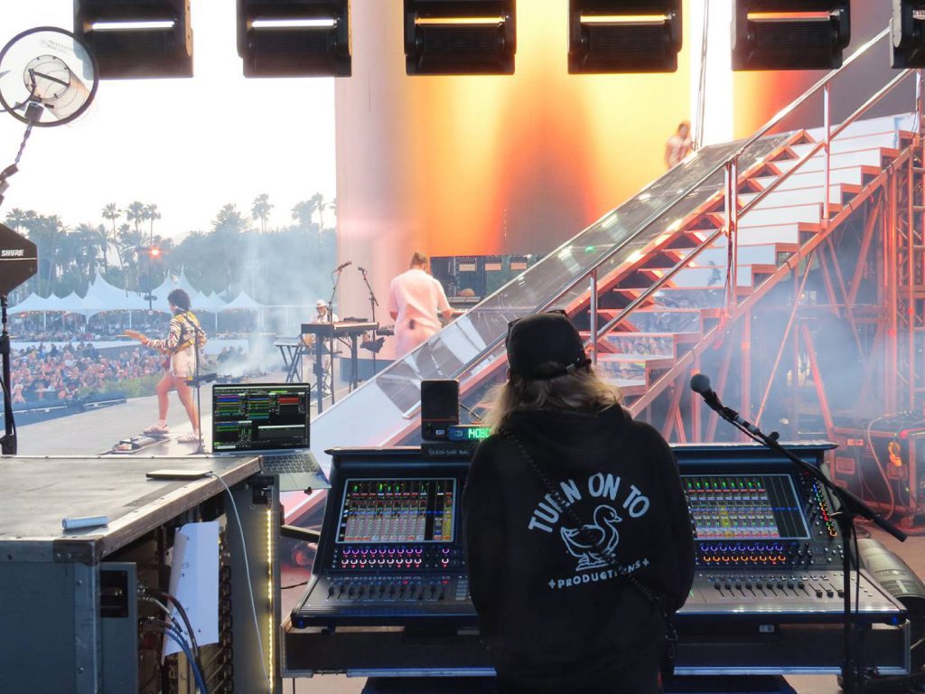Técnico de monitores operando una consola DiGiCo Quantum338 durante el concierto de Benson Boone en Coachella, con vista al escenario y al público.