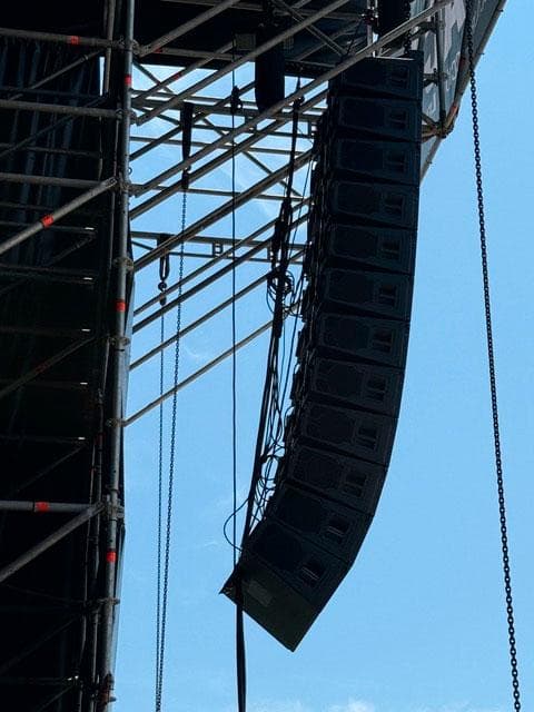 Sistema line array KSL de d&b audiotechnik suspendido en estructura para evento al aire libre, mostrando su diseño curvo para cobertura controlada