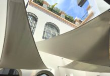 Velas tensadas equipadas con ABSORBRELLA instaladas en la terraza de un hotel urbano, mostrando su integración discreta en estructuras arquitectónicas exteriores.