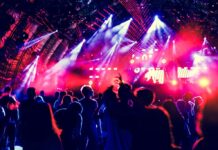 Iluminación profesional con lámparas HID de alto rendimiento en un concierto en vivo con público y efectos visuales dinámicos.