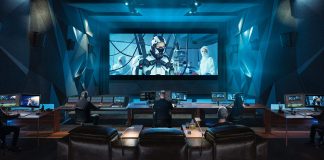 Estudio de postproducción profesional equipado con DaVinci Resolve de Blackmagic Design, donde un equipo de editores y coloristas trabaja en la corrección de color, edición y mezcla de audio de una película de ciencia ficción proyectada en una gran pantalla de cine.