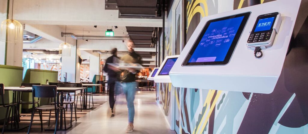 Quioscos de autoservicio con sistema POS para restaurantes y hostelería en el comedor corporativo de Media.Monks, con pantallas táctiles ProDVX y terminales Sjef.