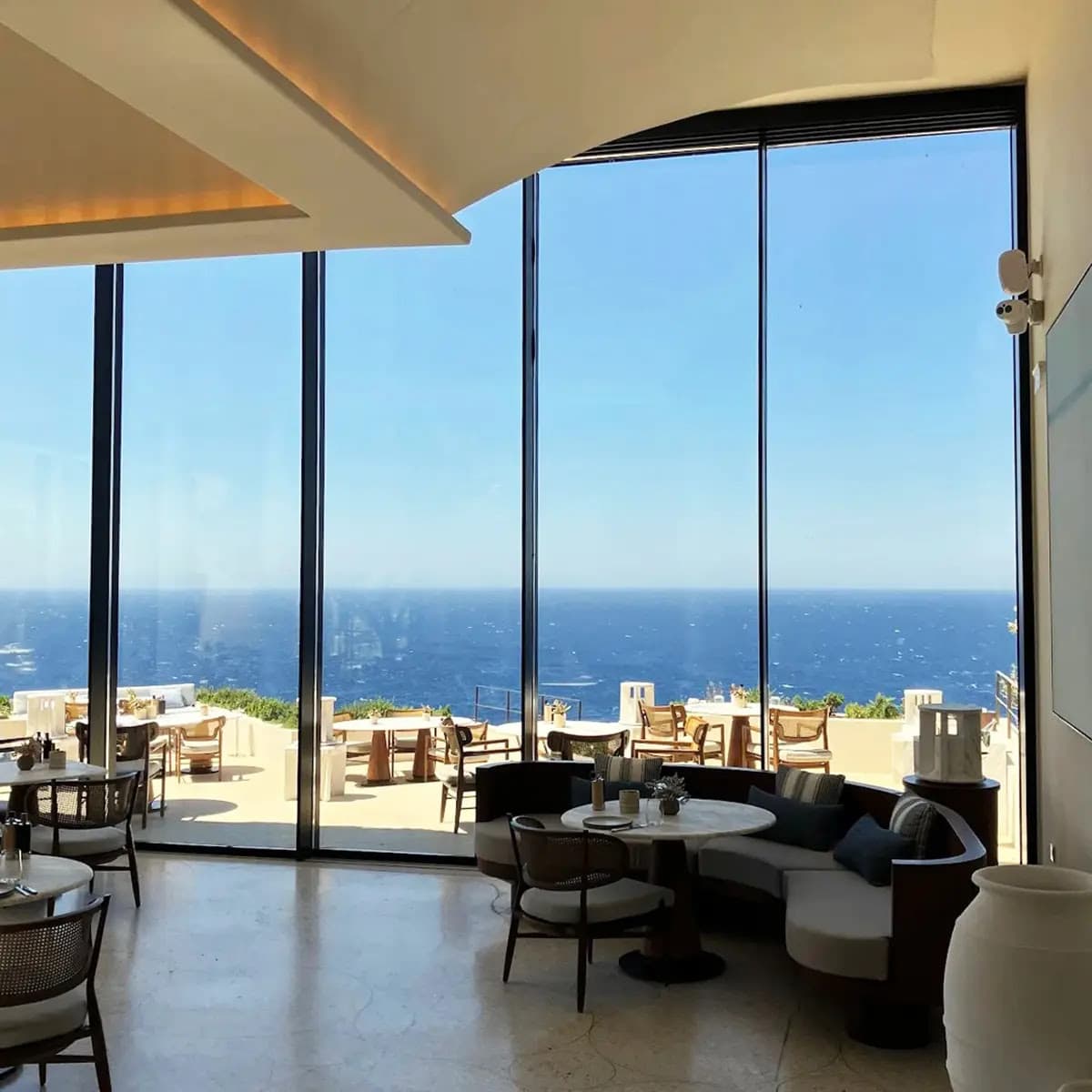 Restaurante con ventanales frente al mar en One&Only Kéa Island, equipado con el sistema de sonido profesional de Biamp en One&Only Kéa Island.