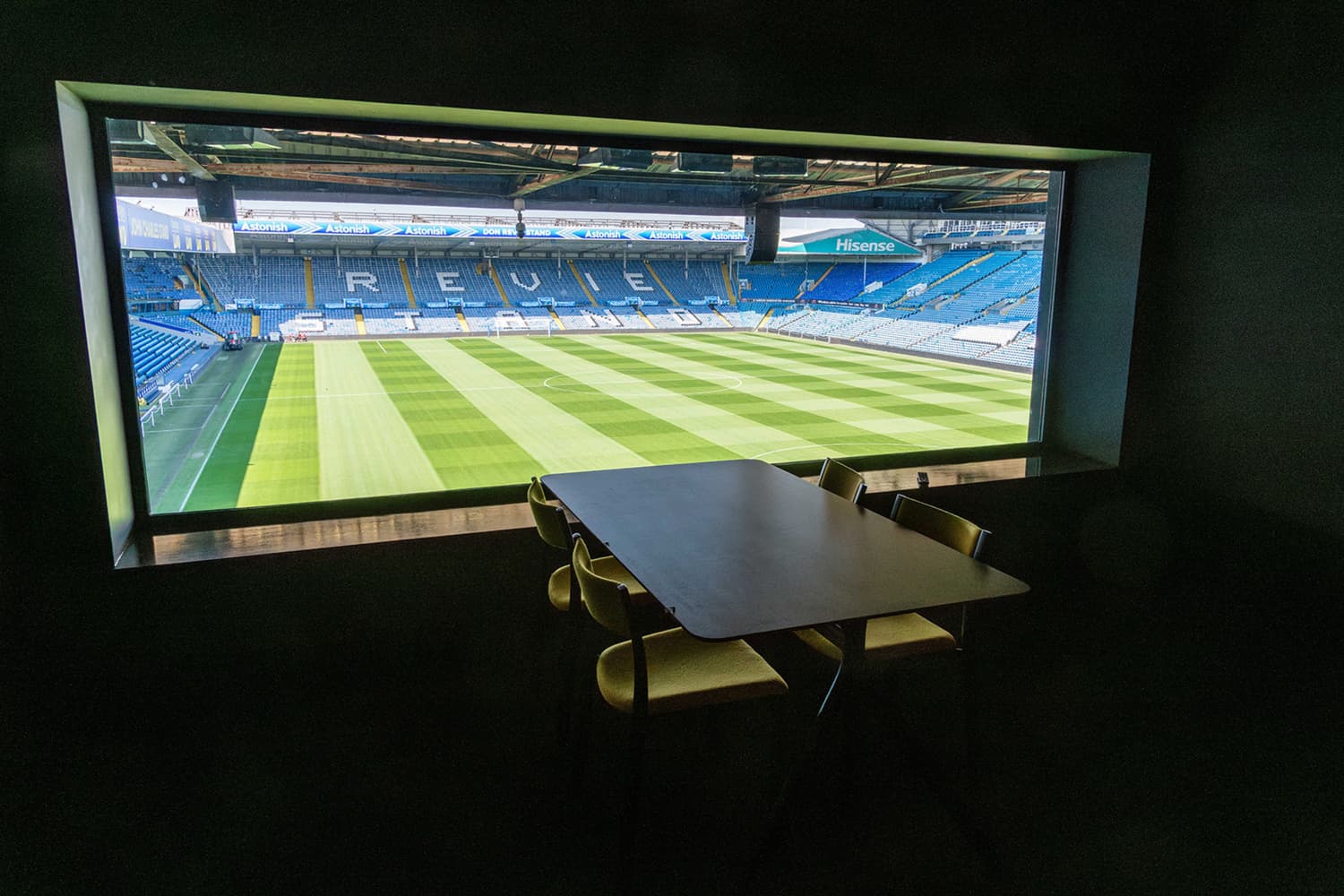 Vista desde un palco o sala VIP con el campo de Elland Road al fondo y los altavoces instalados bajo la cubierta del estadio.