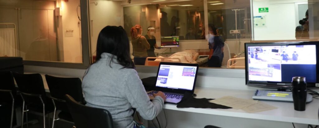 Sala de monitoreo del centro de simulación médica de la Universidad Javeriana, con instructores observando procedimientos clínicos en tiempo real mediante tecnología AREC.