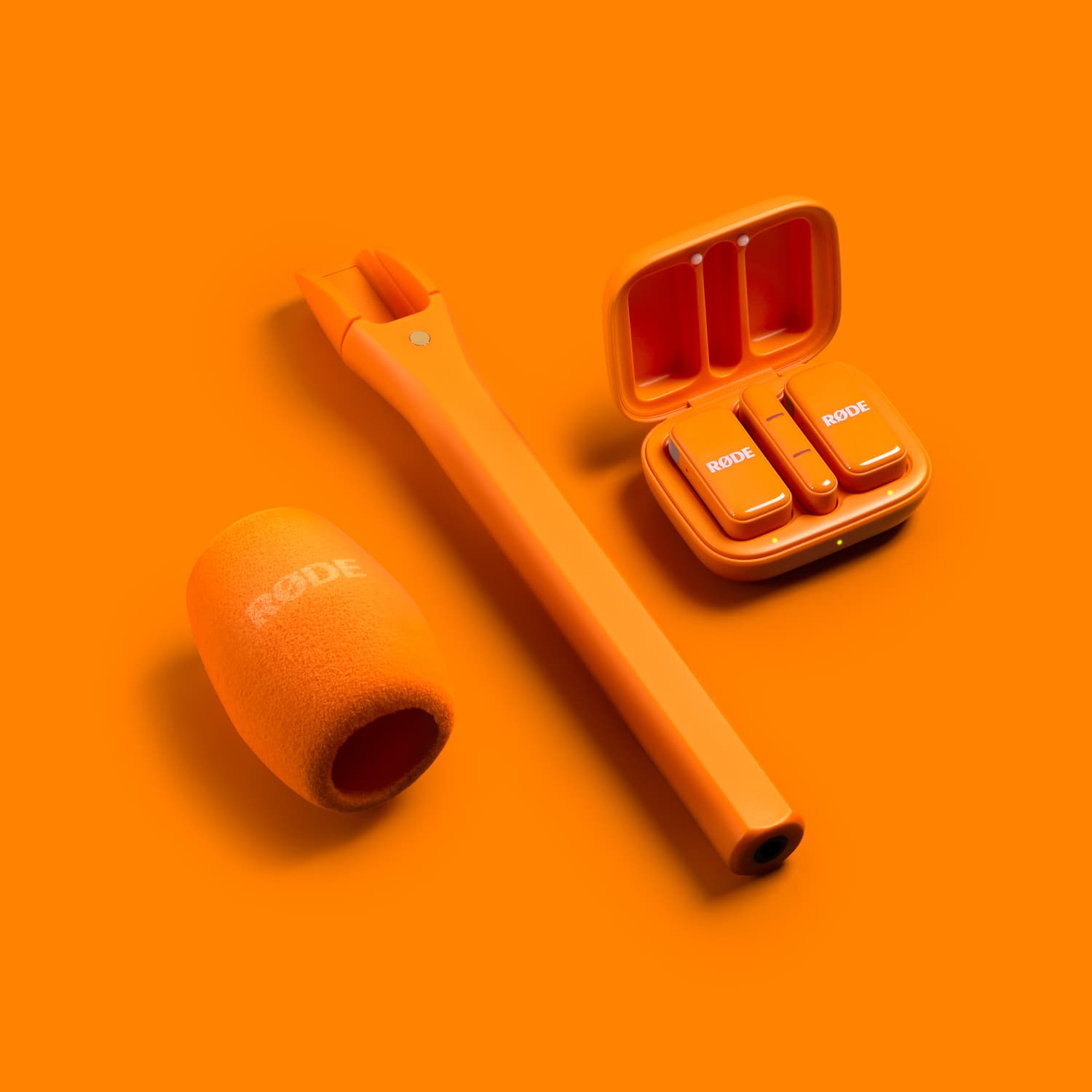 RØDE Interview Micro en color naranja junto al sistema Wireless Micro y su antiviento de espuma, accesorio para convertir el transmisor en un micrófono de mano para entrevistas.
