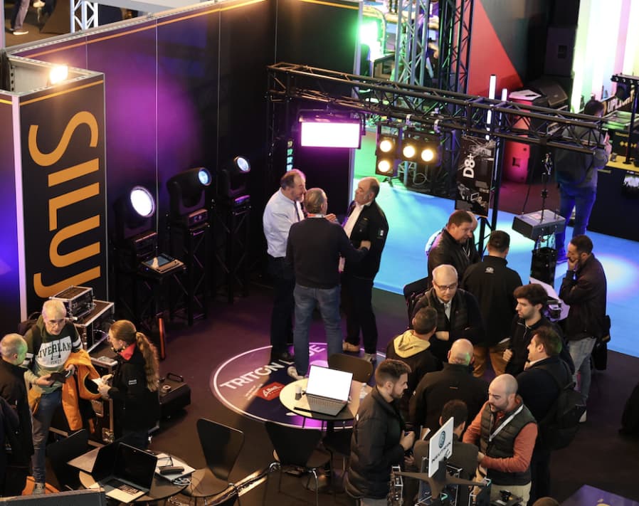 Stand de SILUJ en BITAM 2025 con demostraciones de iluminación Triton Blue y equipos profesionales, rodeado de visitantes y técnicos.