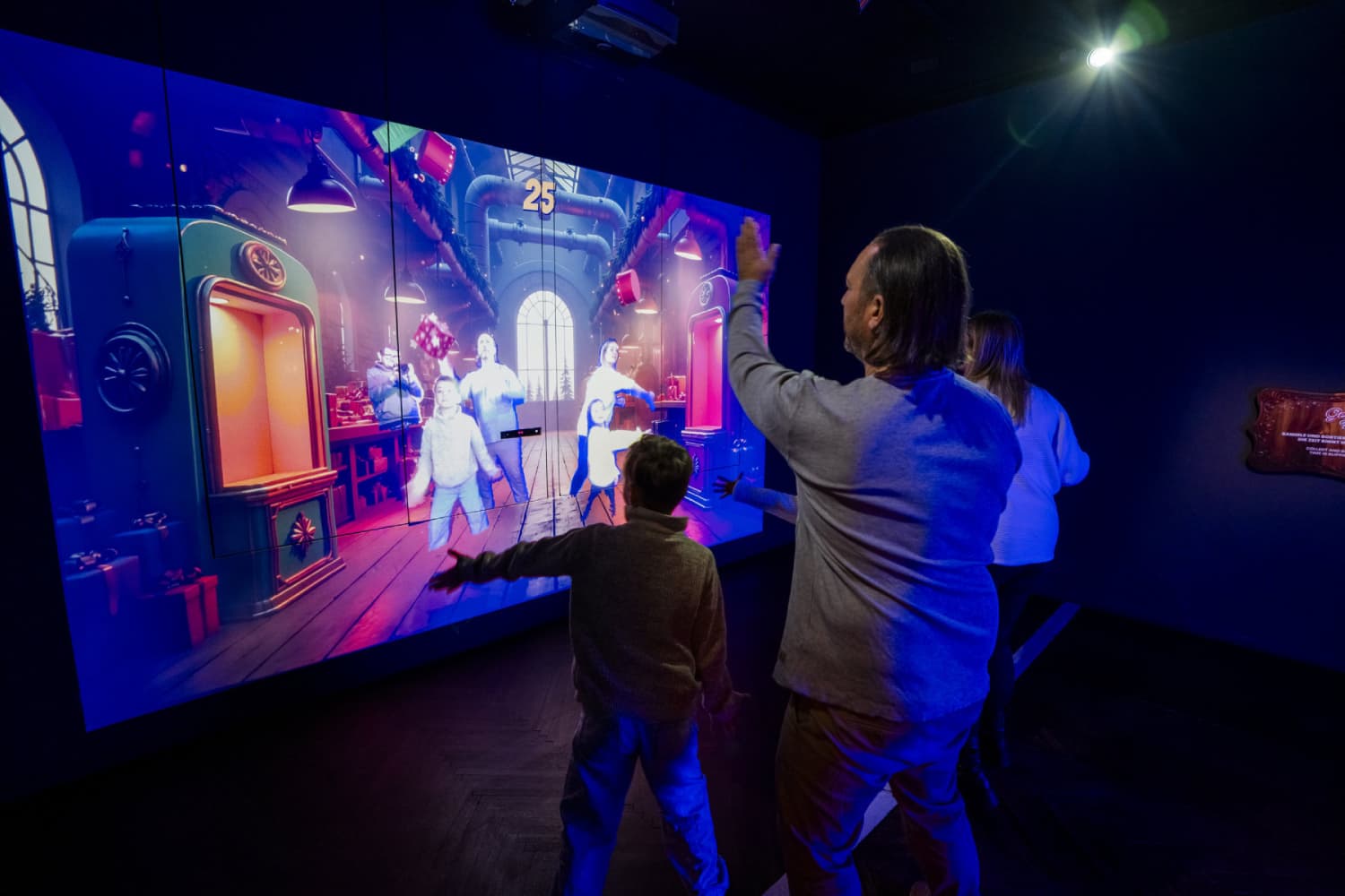 Padres y niños participando en un juego interactivo proyectado con tecnología láser Christie Captiva durante la experiencia inmersiva de Navidad en Bristol.