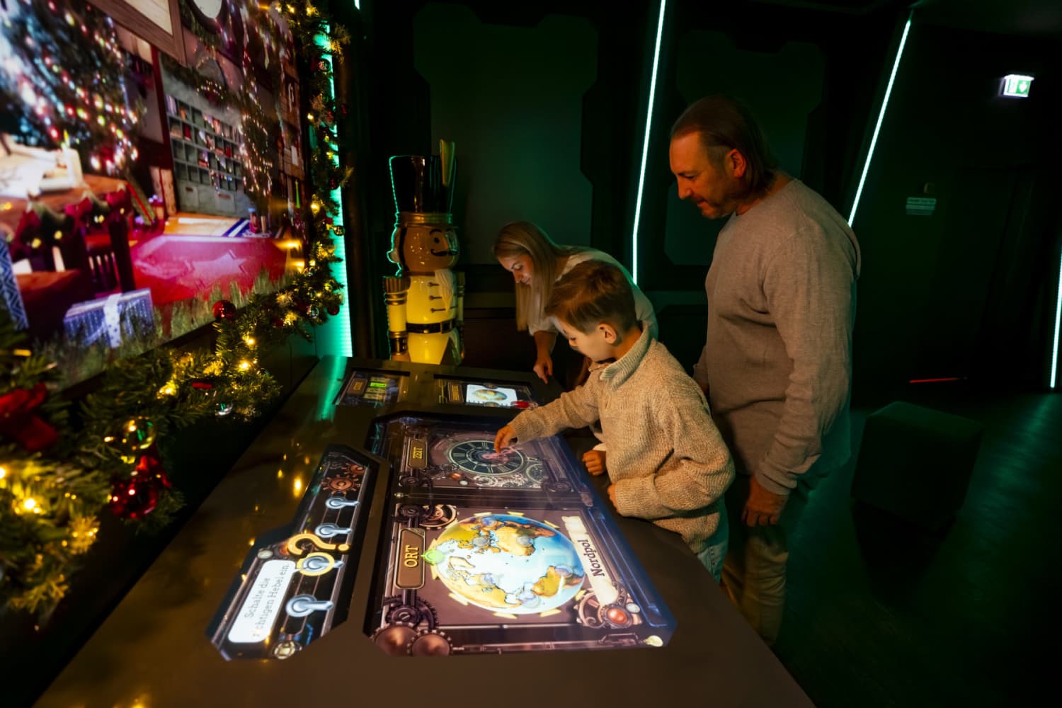Niño y familia usando estaciones interactivas proyectadas mediante proyectores láser Christie Captiva en la atracción "Navidad Encantada" de Planet Ice Bristol.