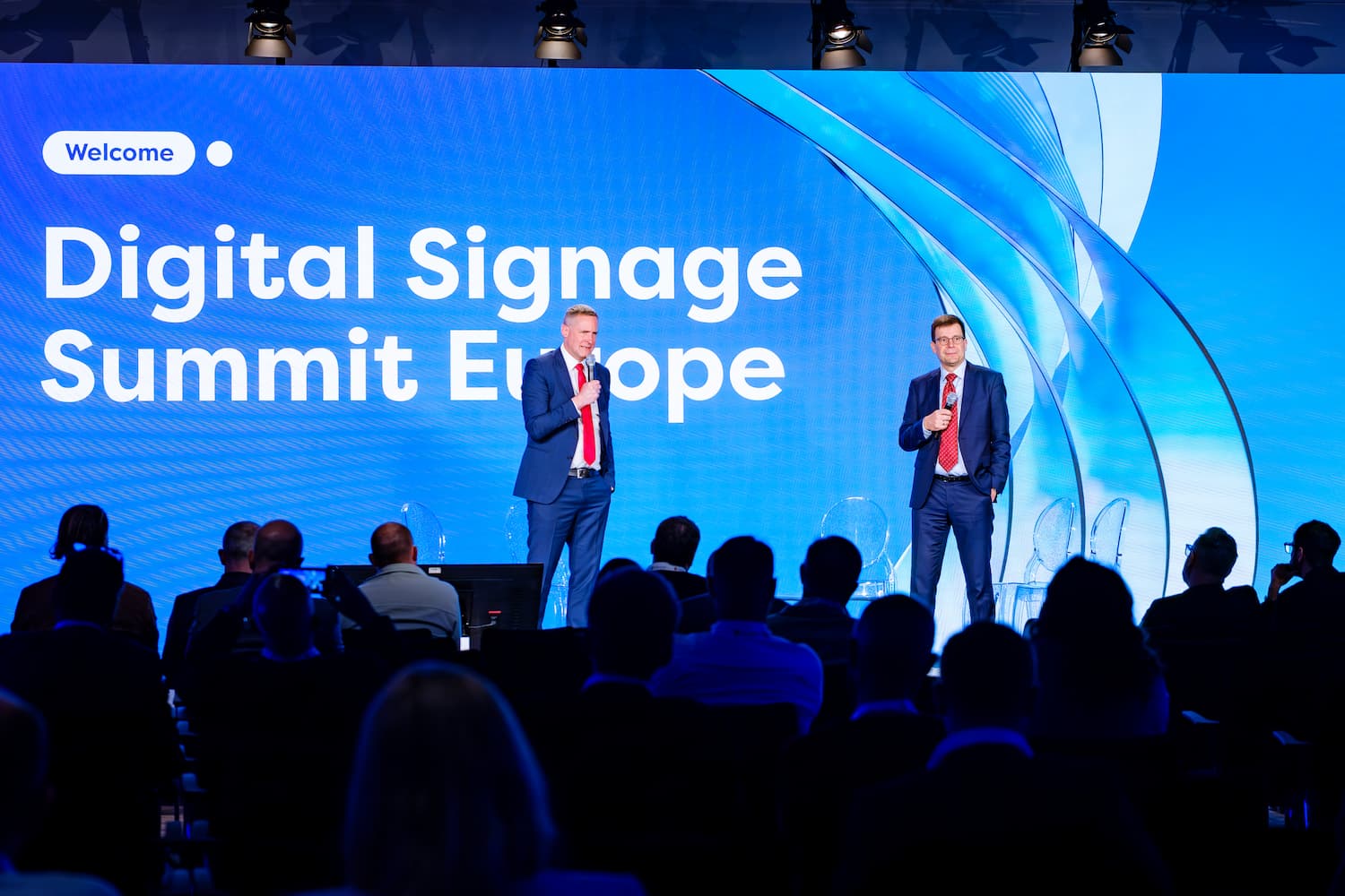 Escenario principal de Digital Signage Summit Europe con dos ponentes durante una presentación ante el público