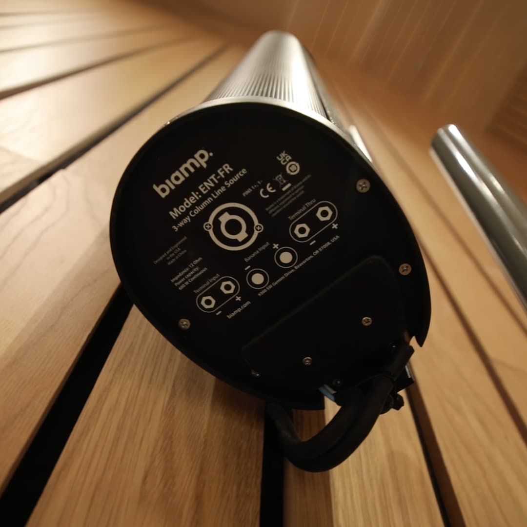 Detalle del altavoz de columna Biamp Desono ENT-FR instalado en pared de madera