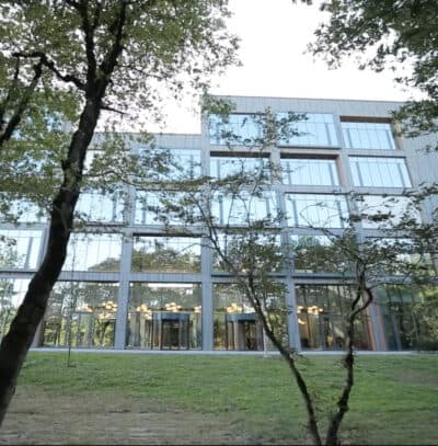 Biamp en la Universidad Internacional de Kutaisi: fachada acristalada del campus rodeada de árboles