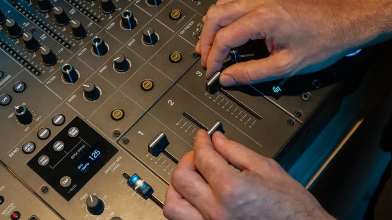 DJ ajustando los faders de un mezclador profesional durante una mezcla con múltiples decks.