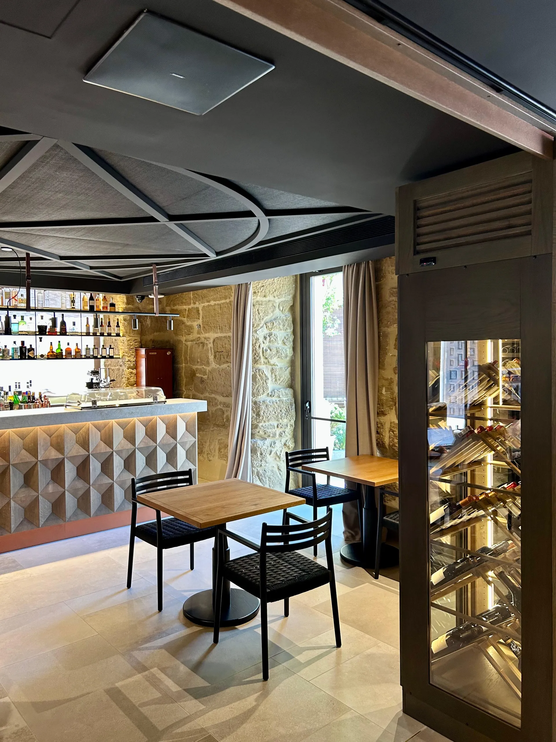 Vinoteca del hotel con altavoz integrado en el techo junto a un muro de piedra