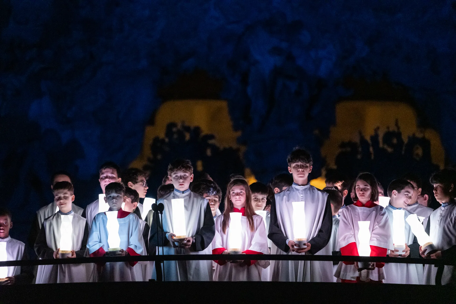 Corales infantiles sosteniendo luminarias integradas como farolillos durante la secuencia inicial de la ceremonia en la Sagrada Familia.