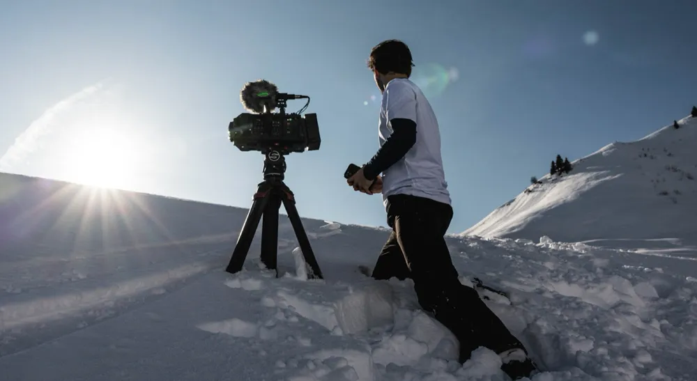 Producción inmersiva en alta montaña: Altitude101 rueda «KICK» con la Blackmagic URSA Cine Immersive 3 Operador de cámara ajusta una Blackmagic URSA Cine Immersive sobre trípode bajo la luz intensa de la nieve en los Alpes