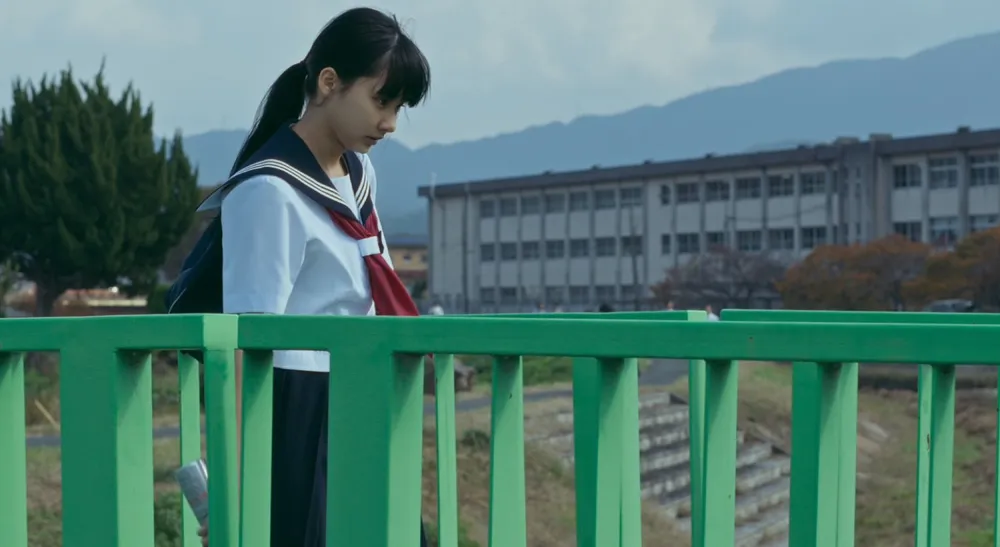 Blackmagic PYXIS 6K en Cry Out: rodar sin frenar la tensión 4 Personaje de Cry Out sobre un puente con montañas al fondo, plano tratado con LUT en el etalonaje