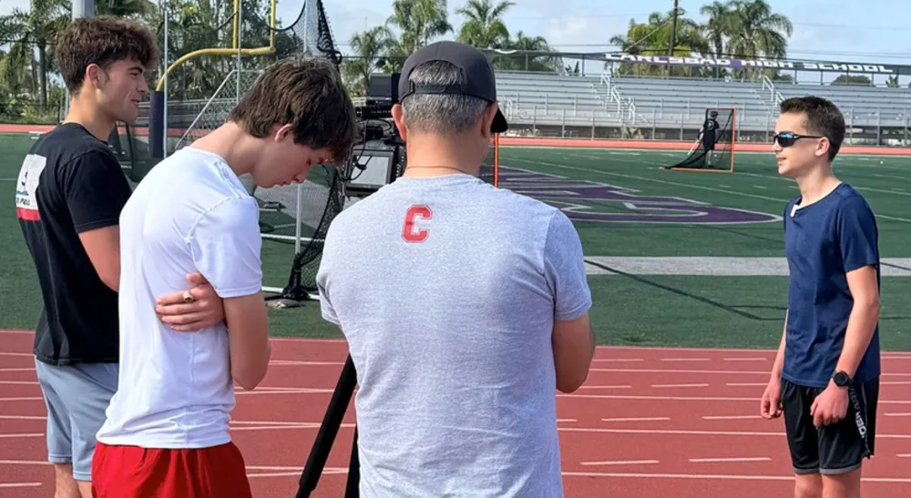 Instructor de la Kids Broadcasting Academy graba una entrevista a estudiantes en la pista de Carlsbad High School