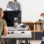 Oficina híbrida con escritorios compartidos equipados con dispositivos Evoko Kleeo y varias personas trabajando