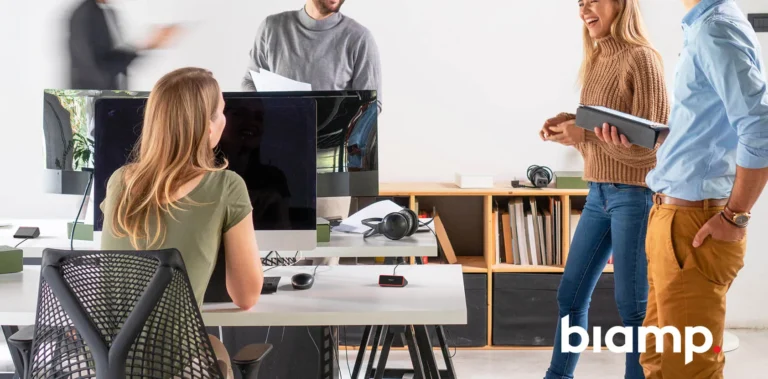 Oficina híbrida con escritorios compartidos equipados con dispositivos Evoko Kleeo y varias personas trabajando