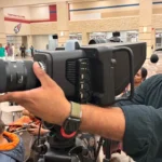 Operador de cámara sujeta una Blackmagic Studio Camera 6K Pro frente al público durante el concurso Thirukkural.