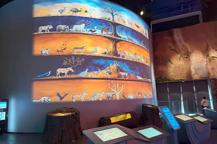 Mural curvo del árbol de la vida proyectado con Christie Jazz Series y estaciones interactivas en la galería Zoo of Extinction