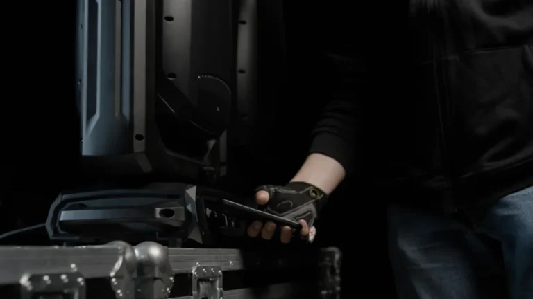 Técnico acercando un teléfono móvil a la base de una cabeza móvil Cameo apoyada sobre un flight case para transferirle la configuración por NFC