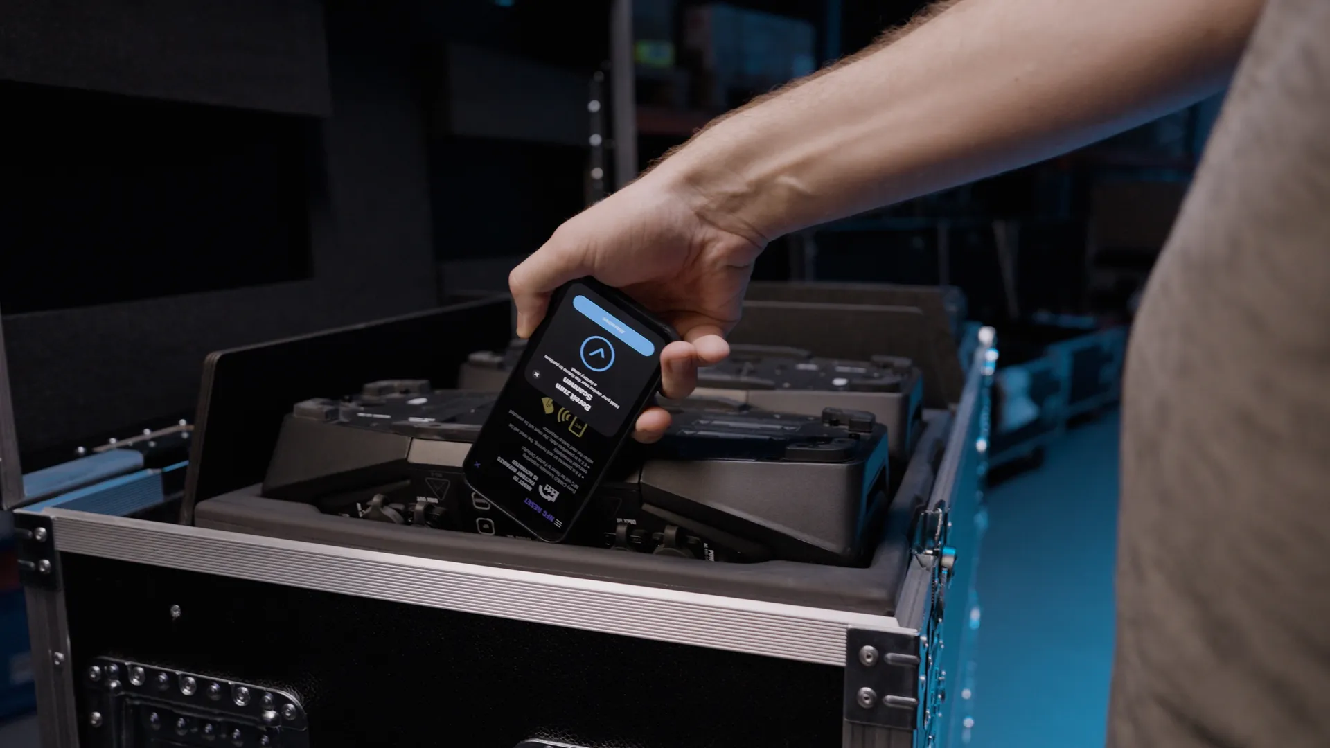 Móvil con la app Cameo CONNECT sobre luminarias guardadas en su flight case en un almacén de material técnico