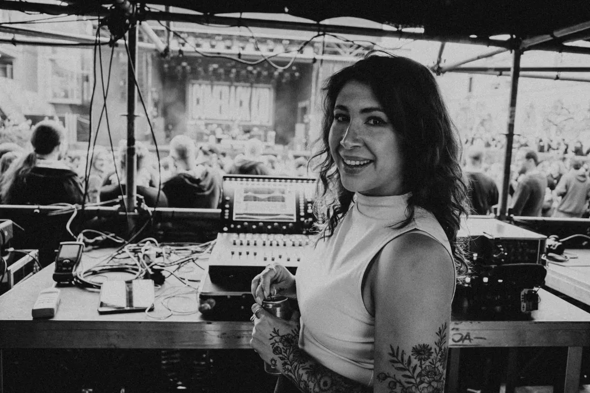 Conni Ettinger en la posición de FOH de un festival al aire libre, junto a la consola y de espaldas al escenario