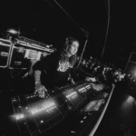 Conni Ettinger mezclando en la consola FOH durante un concierto, con el público alrededor de la posición de control