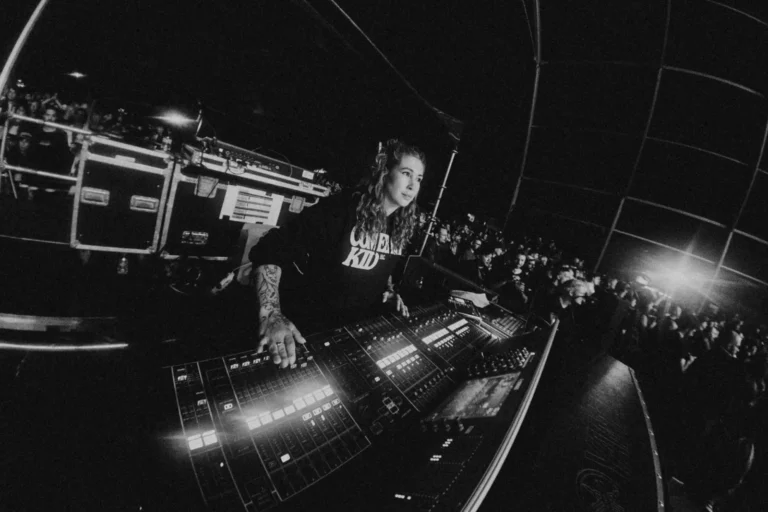 Conni Ettinger mezclando en la consola FOH durante un concierto, con el público alrededor de la posición de control