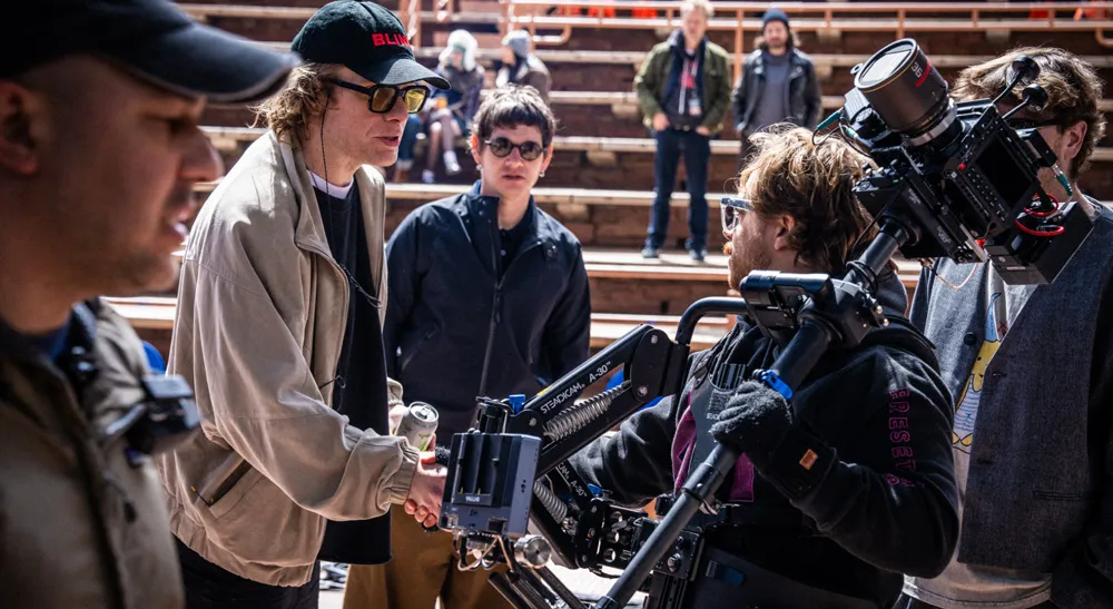 Miembros del equipo de producción conversan junto a un operador con cámara montada en Steadicam en Red Rocks