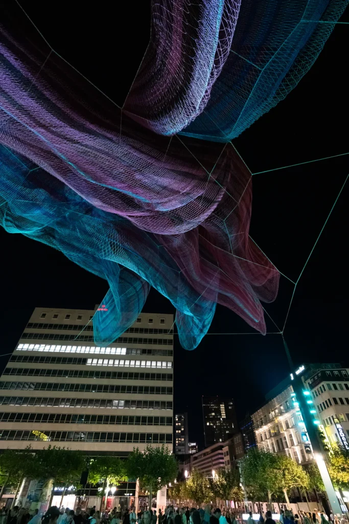 La escultura de red de Janet Echelman iluminada sobre los edificios de la Konstablerwache de Fráncfort