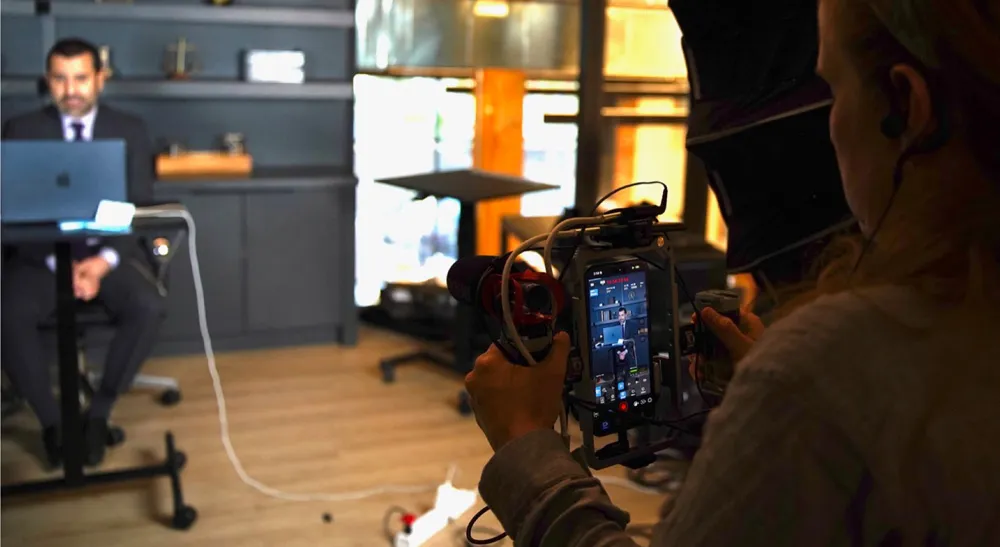 «Legal Queens»: 80 episodios de producción vertical con Blackmagic Camera y equipo mínimo 3 Operadora graba con un iPhone y Blackmagic Camera a un abogado sentado a su mesa, con las ventanas iluminadas del despacho al fondo
