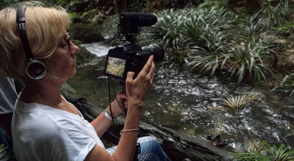 Lisa Marie Russo rueda «Making of Lord of the Flies» con la Pocket 6K Pro de Blackmagic Design 3 Rodaje del documental junto a un arroyo de la selva con una cámara compacta, un objetivo fotográfico y la pantalla abatible desplegada