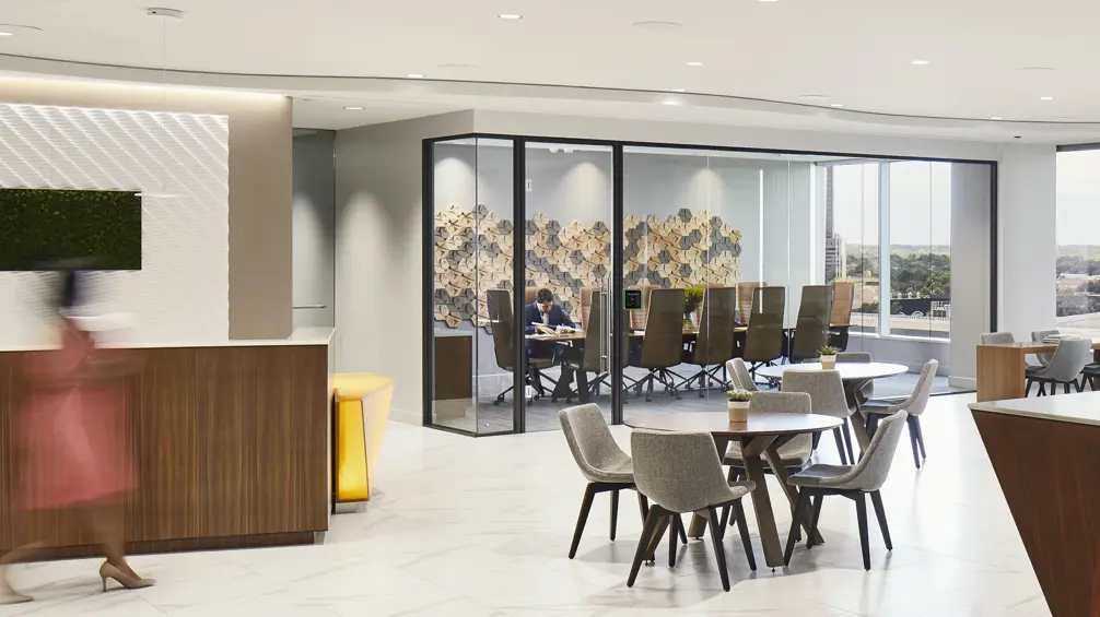 Cómo Firmspace mejora la privacidad acústica en oficinas con Biamp 3 Panel táctil de reserva de sala con indicador luminoso verde junto a la puerta acristalada de una sala de reuniones en una oficina de Firmspace