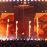 Escenario de festival de música con pirotecnia y videowall durante un concierto en directo, verano 2026