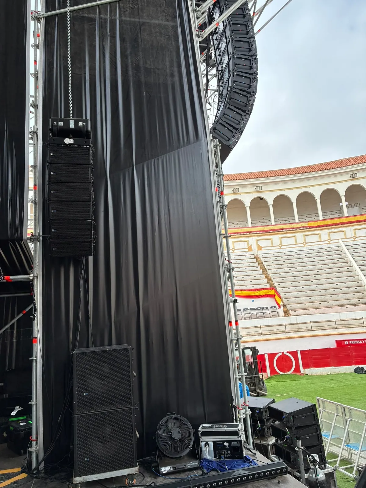 Subgraves apilados en el suelo junto a un array volado en el lateral del escenario de la Plaza de Toros de Melilla