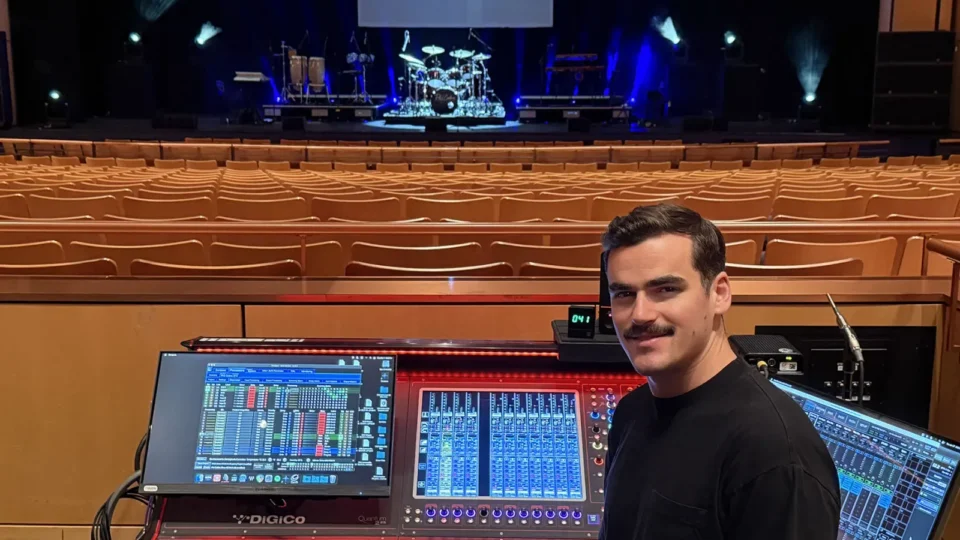 Consola DiGiCo Quantum225 en la mesa de FOH de The Phil Collins Story, con un técnico de sonido supervisando la mezcla