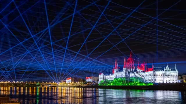 Projection on the Hungarian Parliament Building in the colours of the Hungarian flag, with blue laser beams over the Danube during St Stephen’s Day in Budapest