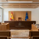 Recreación digital de una sala de vistas con estrado, micrófonos de cuello de cisne, mesa de partes, pantalla mural y cámara de videoconferencia
