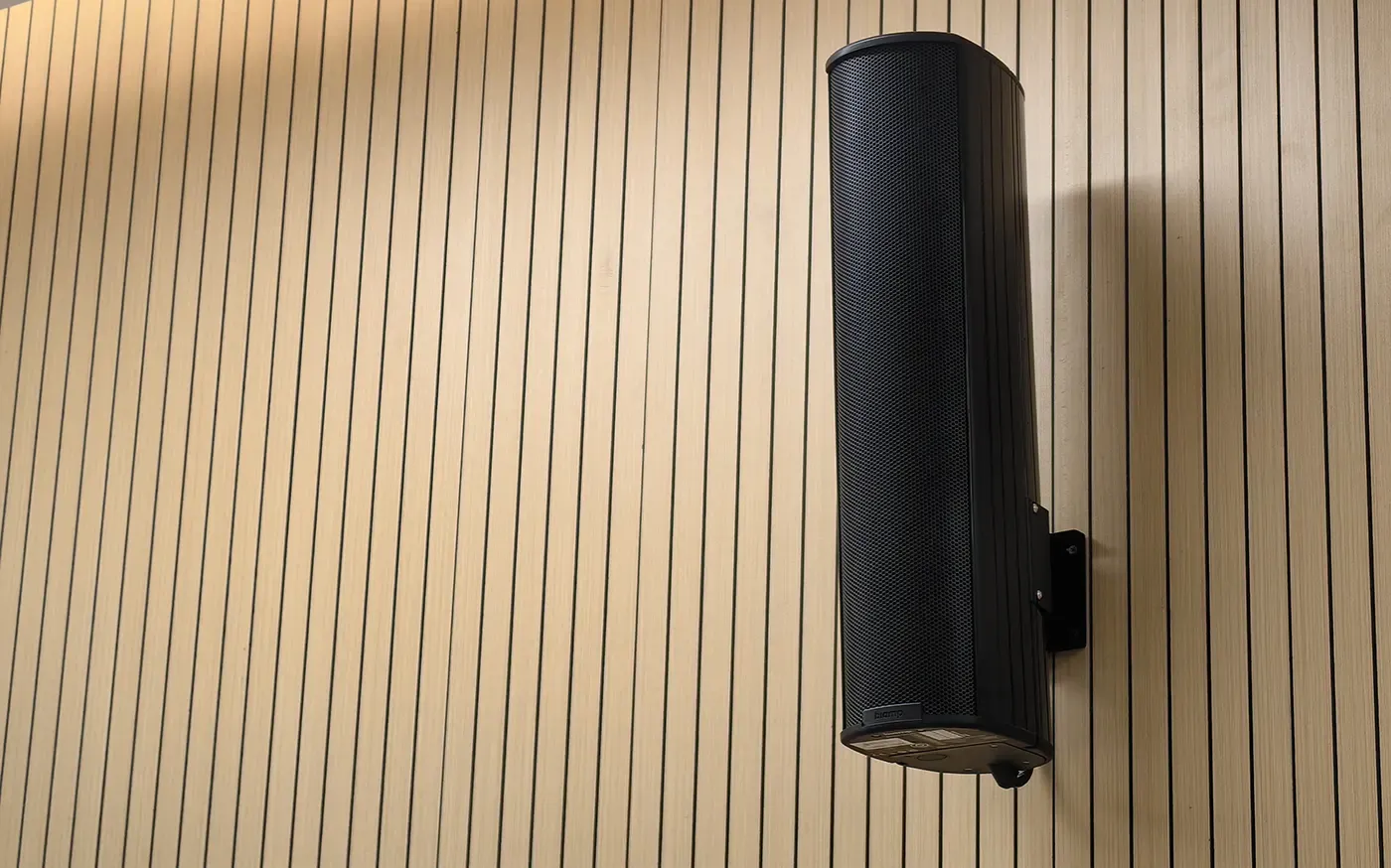 Columna Biamp Desono ENT206 montada en la pared de listones de madera del aula