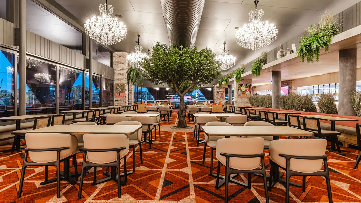 Restaurante del Dakabin Hotel con lámparas de araña, un árbol en el centro de la sala y moqueta de motivos geométricos